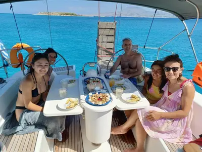 a group of people sitting around a table on a boat at Kristy's House with garden in Chania Town