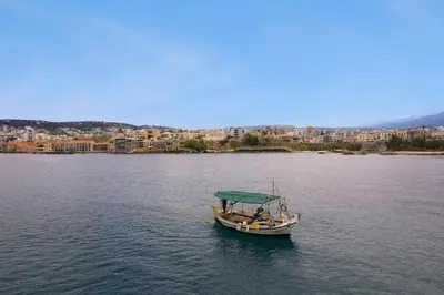 a boat in the water with a city in the background at Waves - Seaside Escape in Chania Town