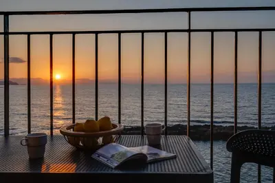 a table with a bowl of fruit on a balcony with the ocean at Waves - Seaside Escape in Chania Town
