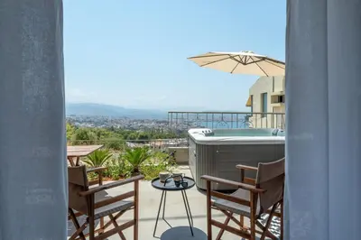 a balcony with a hot tub and chairs and an umbrella at STR Sodi The View in Chania Town