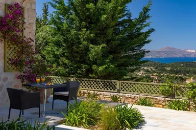 a patio with a table and chairs and a tree at Villa Anthos - Superb panoramic sea and hill views with private pool in Gavalochori