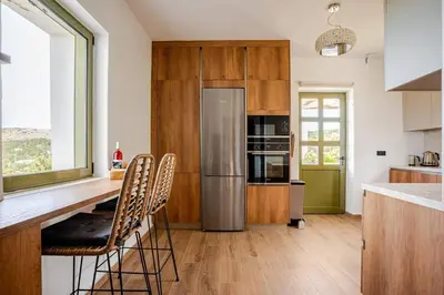 a kitchen with wooden cabinets and a stainless steel refrigerator at Villa Anthos - Superb panoramic sea and hill views with private pool in Gavalochori