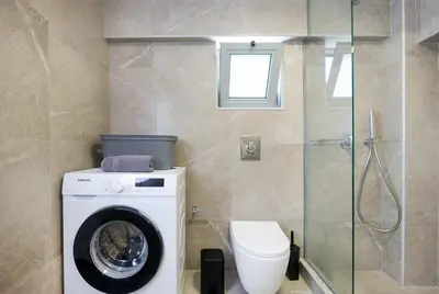 a bathroom with a washing machine and a toilet at Kappa Apartment in Chania Town