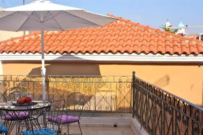a balcony with an umbrella and a table and chairs at La Fiora Old Town Chania in Chania Town