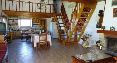 a living room with a dining room and a kitchen with a staircase at Villa Oneiro Tsivaras in Tsivarás