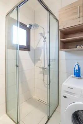 a glass shower stall in a bathroom with a washing machine at Almyrida Bay View House V BY APOKORONAS-VILLAS in Almirida