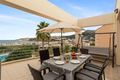 a table with chairs and an umbrella on a balcony at Almyrida Bay View House V BY APOKORONAS-VILLAS in Almirida