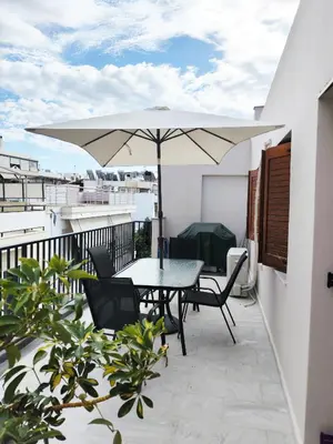 a patio with a table and an umbrella on a balcony at Coastal Retreat in Nea Chora in Chania Town