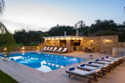 a swimming pool with lounge chairs and a house at Villa Melitini in Souda