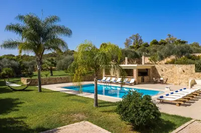 a swimming pool with lounge chairs and a villa at Villa Melitini in Souda