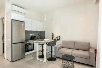 a kitchen with a refrigerator and a table and a couch at Harma City Living in Chania Town