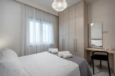 a white bedroom with a bed and a desk at Harma City Living in Chania Town
