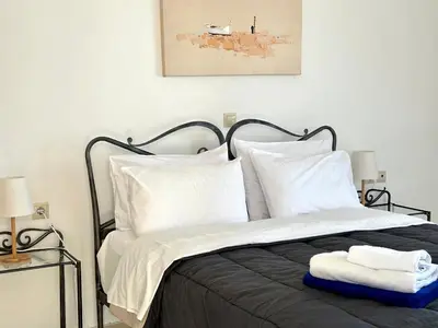 a bedroom with a bed with white sheets and pillows at Aegean View Villa, 2-min Drive to Almyrida Beach in Almirida