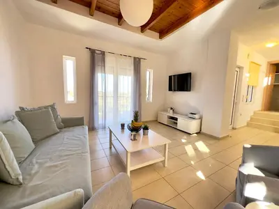 a living room with a couch and a table at Aegean View Villa, 2-min Drive to Almyrida Beach in Almirida