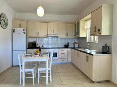 a kitchen with a white table and white appliances at Aegean View Villa, 2-min Drive to Almyrida Beach in Almirida