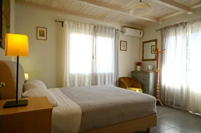 a bedroom with a bed with a lamp and windows at Seaside Cottage in Kato Daratso