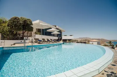 a large swimming pool with chairs and umbrellas at Villa Kera Panorama by PosarelliVillas in Vamos