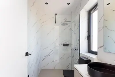 a bathroom with a shower with white marble walls at Villa Zenora in Litsárdha