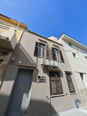 a white building with brown shuttered windows and a door at Casa di Rosa in Chania Town