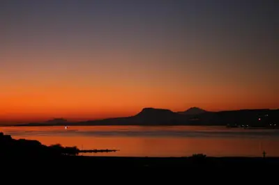 a sunset over the water with mountains in the background at Penthhouse next to the beach in Souda