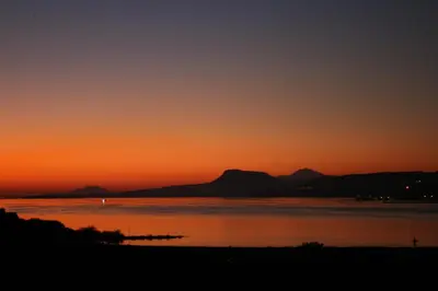 a sunset over the water with mountains in the background at Penthhouse Studio next to the beach in Souda