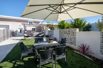 a table and chairs with an umbrella in a yard at Casa di Mina's in Chania in Sirílion