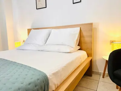 a bed with white sheets and pillows in a room at Kd's apartment B in Chania Town