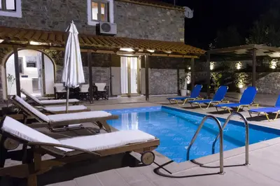 a swimming pool with lounge chairs and an umbrella at Beautiful Villa in Zounákion
