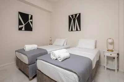 two twin beds in a room with white walls at The White Marble Luxury City Apt in Chania Town