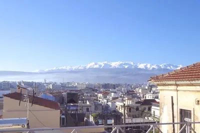 a city with snow covered mountains in the background at Venetian House in Chania Town
