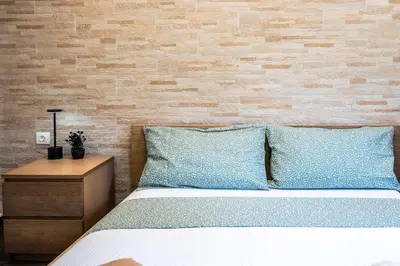 a bed with blue pillows and a brick wall at Kamari Petit Studio & Apartment - Chania in Chania Town
