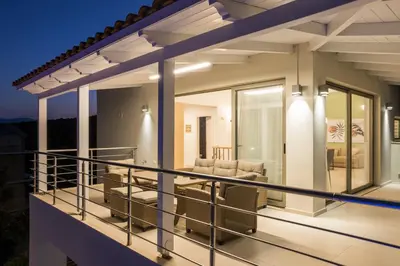 a balcony of a house with glass doors and furniture at Olive Chrysi Luxury Villa with in-room plunge pool in Chania Town