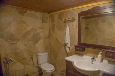 a bathroom with a sink and a toilet and a mirror at Diving into silence - Traditional Stone House in Kakópetros