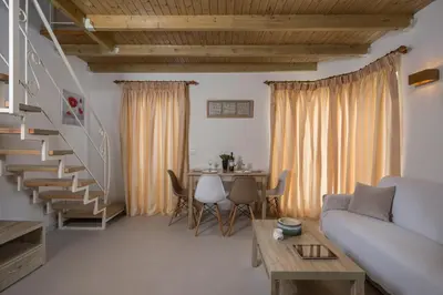 a living room with a couch and a spiral staircase at Pantanassa Villas in Agia Marina Nea Kydonias