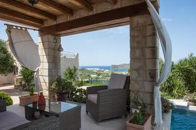 a patio with a table and chairs and a pool at Pantanassa Villas in Agia Marina Nea Kydonias