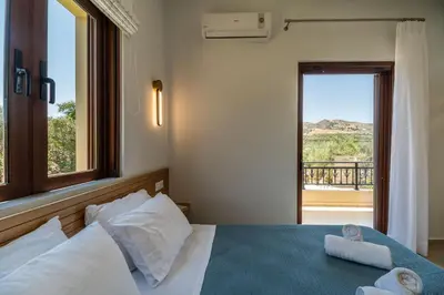 a bedroom with a bed with a view of a balcony at Villa Aetheria by PosarelliVillas in Plátanos