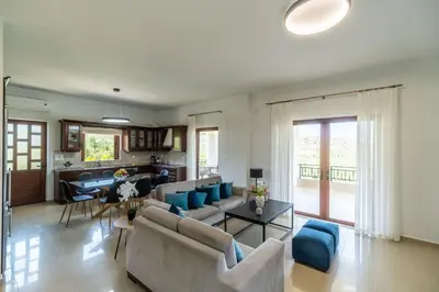 a living room with couches and a table and a kitchen at Villa Aetheria by PosarelliVillas in Plátanos