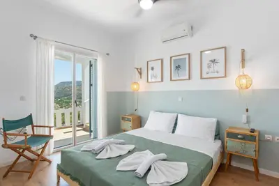 a bedroom with a bed and a chair and a window at Villa Helissie in Vamos
