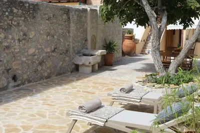 a patio with two lounge chairs and a stone wall at Tholos by Praxithea Stone House & Pool in Gavalochori
