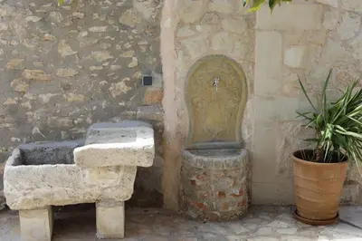 a stone sink next to a stone wall with a fountain at Tholos by Praxithea Stone House & Pool in Gavalochori
