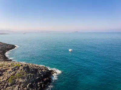 a boat in the ocean next to a rocky shore at Tersanas Sea Front Villas in Tersanas