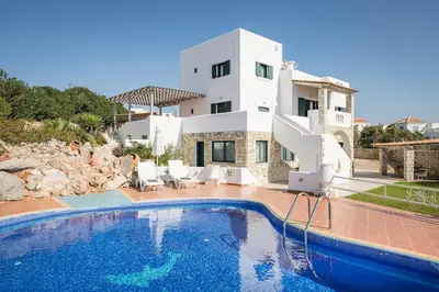 a villa with a swimming pool in front of a house at Tersanas Sea Front Villas in Tersanas