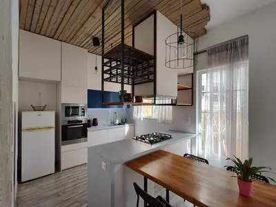 a kitchen with white cabinets and a wooden table at Superior Apartment Near Beach in Chania Town