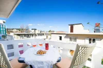a table with wine glasses and a plate of food on a balcony at Irini Apartment I in Kalyves
