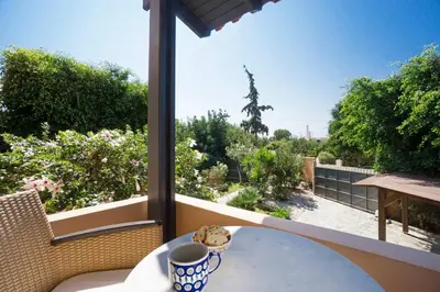 a table on a balcony with a view of a garden at Villa Olivo Kampani in CHQ