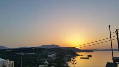 a sunset over a body of water with the sun setting at Paradise in Áyios Andhréas