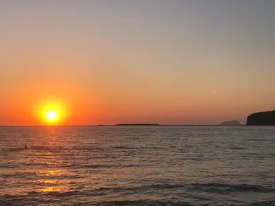 a sunset over the ocean with the sun setting at Perseus Sailing Cruises in Souda