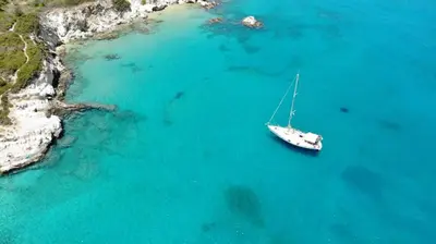 a boat in the water next to a beach at Perseus Sailing Cruises in Souda