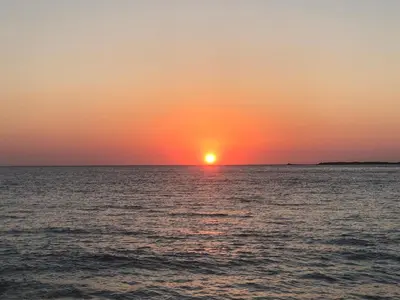 a sunset over the ocean with the sun in the horizon at Perseus Sailing Cruises in Souda