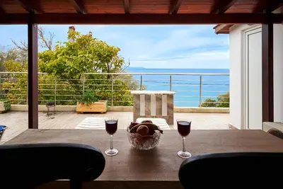 a table with two glasses of wine on a balcony at Seaside House in Chania Town